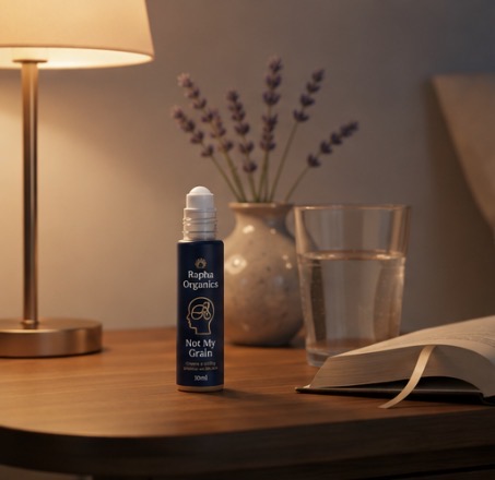 Not My Grain 10ml roll-on bottle on a wooden bedside table with lavender, a book and a warm lamp