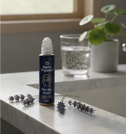 Not My Grain 10ml roll-on bottle on a marble desk near a window with lavender and a glass of water